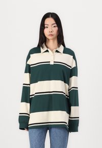 Groen en crèmekleurige gestreepte polo met lange mouwen en een kraag, met zwarte accentstrepen en een relaxte pasvorm.