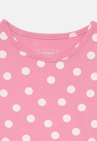 Ροζ κοντομάνικο μπλουζάκι με στρογγυλή λαιμόκοψη, που διαθέτει επαναλαμβανόμενο σχέδιο με λευκές βούλες σε όλη την επιφάνεια. Είναι ορατή η ετικέτα της μάρκας.