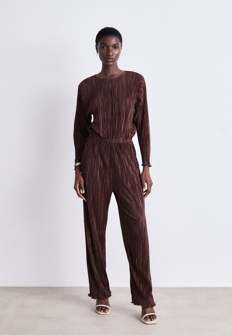 Combinaison bordeaux avec des rayures horizontales, manches longues, taille élastique et jambes évasées. Présente un tissu texturé et une coupe décontractée.