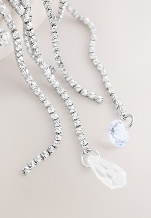 Silver-toned chandelier earrings featuring a chain of clear crystals and two distinct pendants: a round blue gemstone and a clear teardrop.