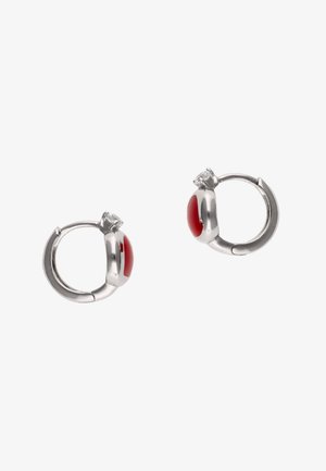 Srebrne kolczyki-koła z zaokrąglonym czerwonym emaliowanym wypełnieniem i małymi akcentami z przezroczystych kamieni szlachetnych na białym tle.