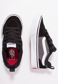 Sneaker in suede nero e mesh con una striscia laterale bianca, lacci neri, una fodera interna rossa e una suola in gomma bianca testurizzata.