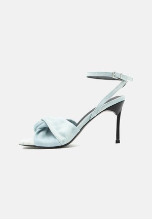 Ανοιχτό μπλε σουέντ ψηλοτάκουνο σανδάλι με μπουκλωτό μπροστινό λουράκι και λεπτό λουράκι στον αστράγαλο με αγκράφα σε μαύρο τακούνι στιλέτο.
