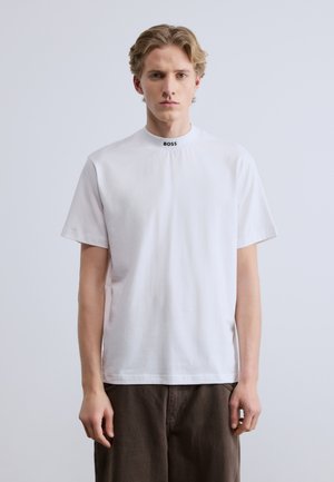 Biała bawełniana koszulka z wysokim dekoltem, z czarnym logo "BOSS" przy kołnierzu. Krótkie rękawy i luźny krój.