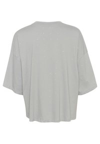 Lys grå t-shirt med korte ærmer og afslappet pasform, der har et prikket mønster af små, glinsende udsmykninger over stoffet.