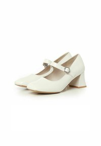 Zapatos Mary Jane de charol blanco con punta redonda, correa con hebilla en el empeine y tacón medio tipo bloque.