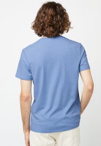 Blauw T-shirt met korte mouwen, een ronde hals en een zachte, gestructureerde stof. De achterkant heeft een klein lusdetail bij de kraag.