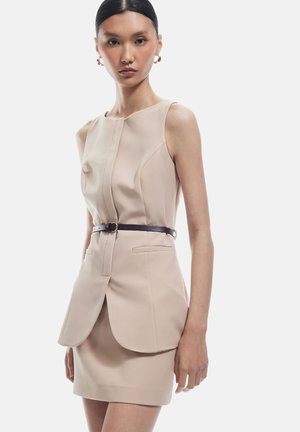 Beige op maat gemaakt jurk met een aansluitende lijfje, geplooide details en een contrasterende donkere riem. Beschikt over een slanke silhouet en subtiele zakken.