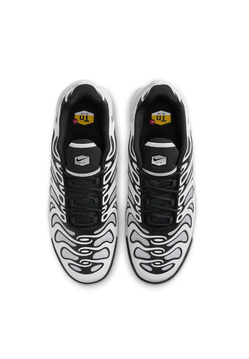 Des baskets Nike avec un design ondulé noir et blanc, en matériaux en mesh et synthétiques, présentant un système de laçage noir et une semelle à air visible.