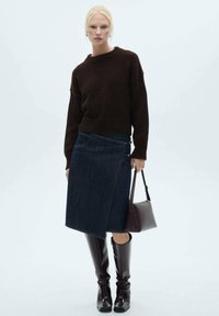 Dunkelbrauner gestrickter Pullover, Denim-Wickelrock, knielange glänzend braune Stiefel und eine kleine burgunderfarbene Handtasche. Einfaches und modernes Design.