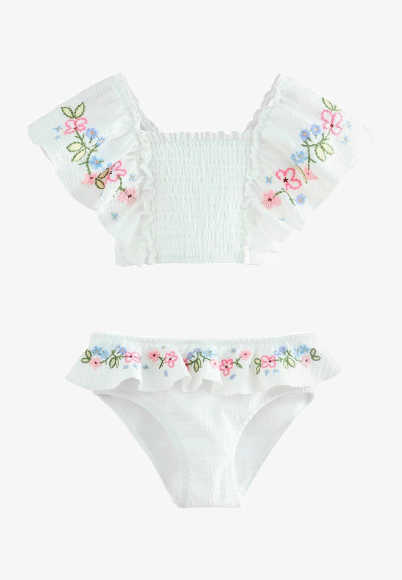 Maillot de bain deux pièces blanc avec manches volantées et taille, décoré de motifs floraux brodés en rose, bleu et vert.