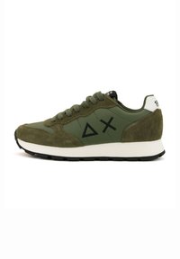 Sneakers verde oliva con un mix di textures lisce e scamosciate, simboli triangolari e incrociati, lacci neri e un accento bianco sul tallone.