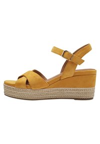 Sandalia de cuña de ante amarillo con correas cruzadas, correa para el tobillo ajustable y plataforma envuelta en yute. Presenta un upper liso y una suela texturizada.