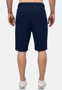 Marineblauwe shorts met een elastische tailleband, een trekkoord en twee achterzakken. Gladde textuur en knielange ontwerp.