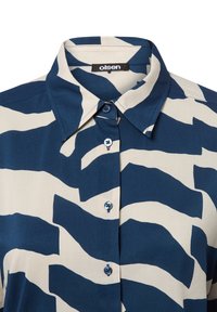 Collared shirt with a blue and cream wavy pattern, made of lightweight fabric. Features five blue buttons along the front.