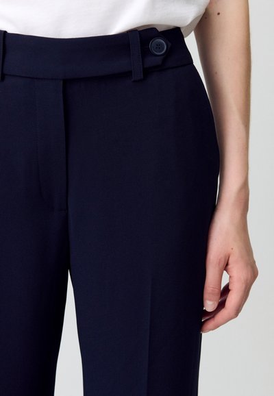 Pantalones azul marino con una textura suave, que cuentan con un cierre de botón y bolsillos laterales. Ajuste entallado con un pliegue en la parte delantera.
