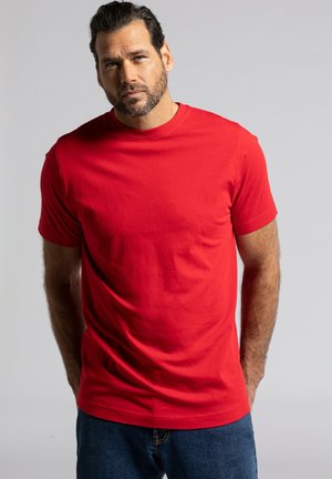 Rotes Baumwoll-T-Shirt mit Rundhalsausschnitt und kurzen Ärmeln, das eine glatte Textur und einen lockeren Schnitt aufweist. Getragen mit blauen Jeans.