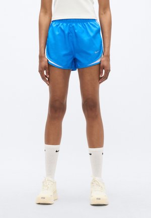 Blauwe sportbroekjes met witte strepen aan de zijkant, een elastische tailleband en een klein logo. Gekozen met witte sportsokken en lichtgekleurde sneakers.