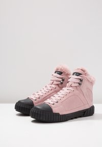 Zapatillas altas de ante rosa con punta de goma negra, cuello acolchado y diseño con cordones. Presentan detalles de hardware plateado.