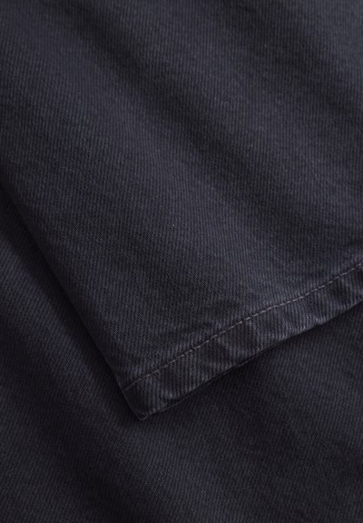 Tume meresinine kangas, millel on peen diagonaalne ribakujundus. Servad on korralikult õmmeldud, näidates sujuvat ja ühtlast viimistlust.