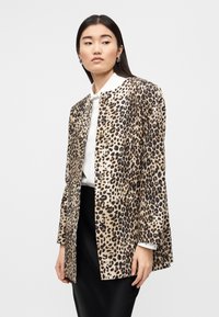 Σακάκι σε λεοπάρ σχέδιο σε μπεζ και καφέ αποχρώσεις, με ίσια κοπή, μακριά μανίκια, κλείσιμο με κουμπιά και απαλό ύφασμα.