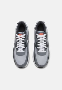 Παπούτσια αθλητικά Nike σε γκρι και μαύρο με λείο συνθετικό άνω μέρος, λευκές κορδόνες και υφή στη σόλα με μαύρες λεπτομέρειες.