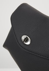 Svart läderkuvertväska med en strukturerad yta, försedd med en rundad klaff och ett silverfärgat metallknäpp för säkerhet.