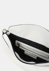 Borsa a mano in pelle bianca con un design arrotondato, dotata di un interno nero e una tasca con zip. L'etichetta riporta la scritta "ERMANNO."