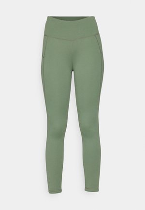 Zöld sportleggings magas derékkal, rugalmas anyagból készült, lapos varrásokkal és sima textúrával.