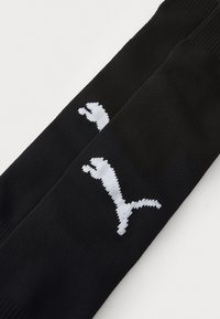 Zwarte sokken met ribbelstructuur, voorzien van een opvallend wit Puma-logo op één kant. Zacht materiaal met een aansluitend ontwerp.