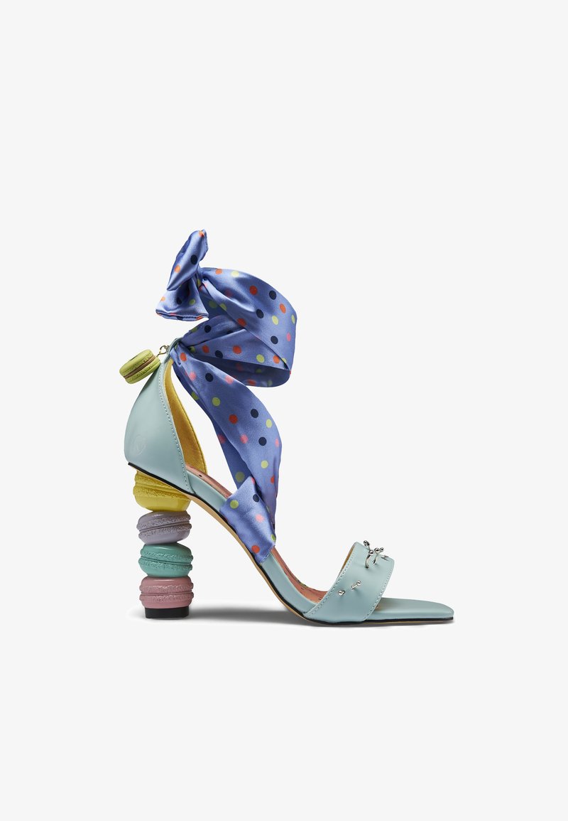 Ανοιχτό μπλε σανδάλι με ψηλό τακούνι σε παστέλ σχήμα μακαρόν και μωβ κορδέλα με πουά δεμένη στον αστράγαλο.