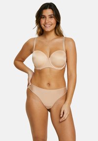 Ensemble de lingerie en beige clair, comprenant un soutien-gorge et une culotte assortis, avec un tissu lisse, un soutien-gorge à armatures, des bretelles réglables et un design minimaliste.