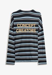 Hosszú ujjú fekete póló kék és fehér vízszintes csíkokkal. A hátsó oldalán vastag, arany betűkkel "KONCEPCIÓK LÉTREHOZÓI" felirat található.