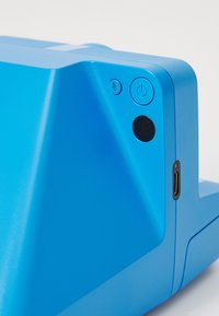 Blue electronic device corner featuring power and flash buttons and a USB-C port on a smooth, angular plastic surface.