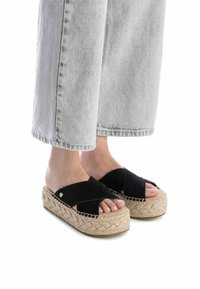 Sandalias de esparto de ante negro con tiras entrelazadas y puntera abierta. Suela de cuña envuelta en yute, con un patrón tejido.