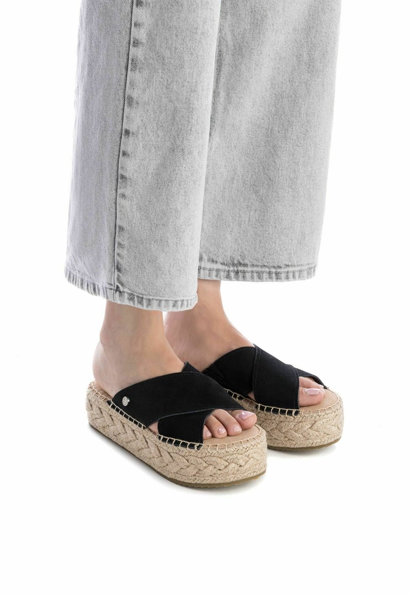 Sandalias de esparto de ante negro con tiras entrelazadas y puntera abierta. Suela de cuña envuelta en yute, con un patrón tejido.