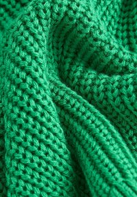 Texturiertes, grünes Strickgewebe mit lockerer Webart, das eine lebendige, einheitliche Farbe und weiche Textur zeigt, ideal für Kleidung oder Decken.