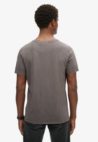 Camiseta de algodón gris con mangas cortas, cuello redondo y un corte holgado. La tela tiene un acabado ligeramente texturizado.