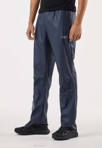 Tummansiniset vettähylkivät housut, joissa on sileä pinta, joustava vyötärö, sivutaskut ja vasemman reiden logo-yksityiskohdat.