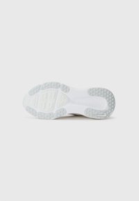 Semelle de sneaker blanche avec des zones de grip en caoutchouc gris texturé et une section médiane lisse sur fond gris clair.
