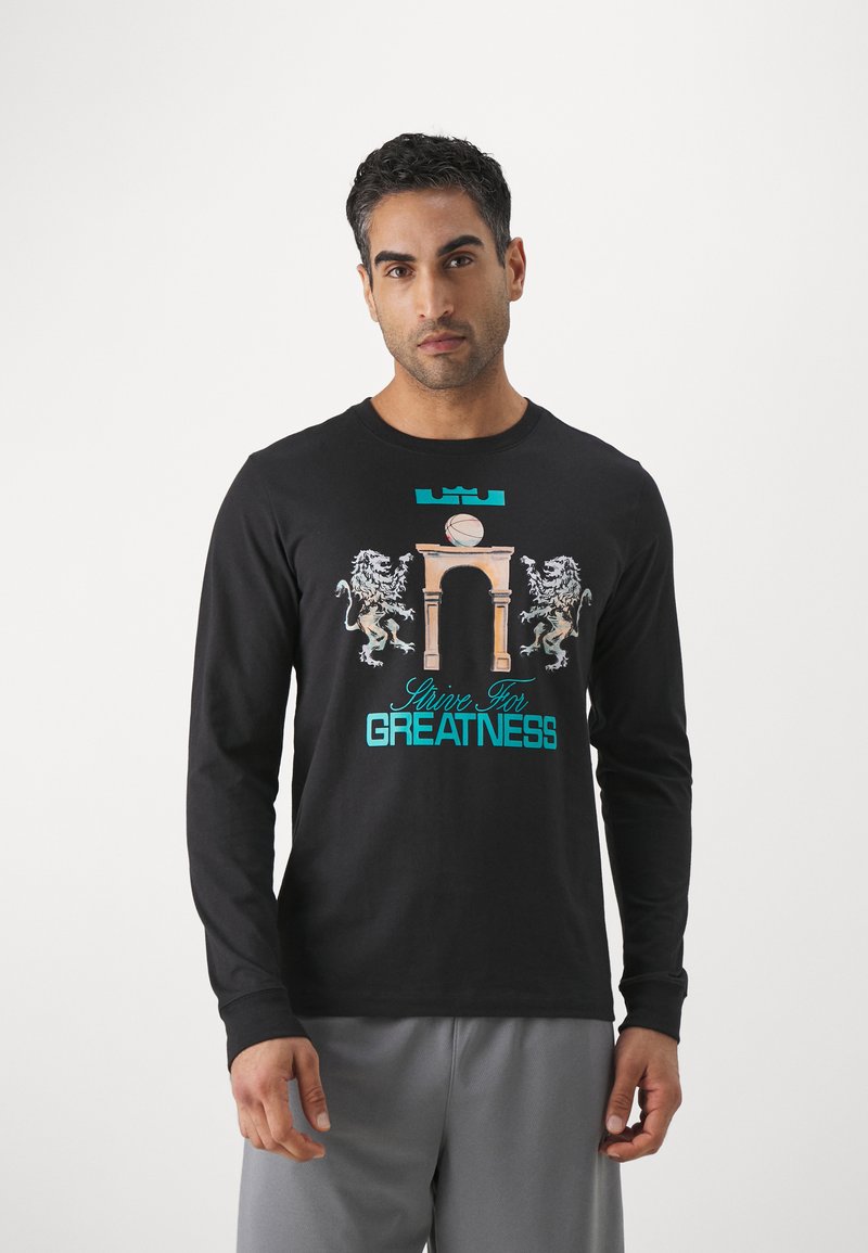 Black long-sleeve t-shirt made of cotton, featuring a graphic design with lions and an arch. Text reads "Strive For Greatness" in turquoise.