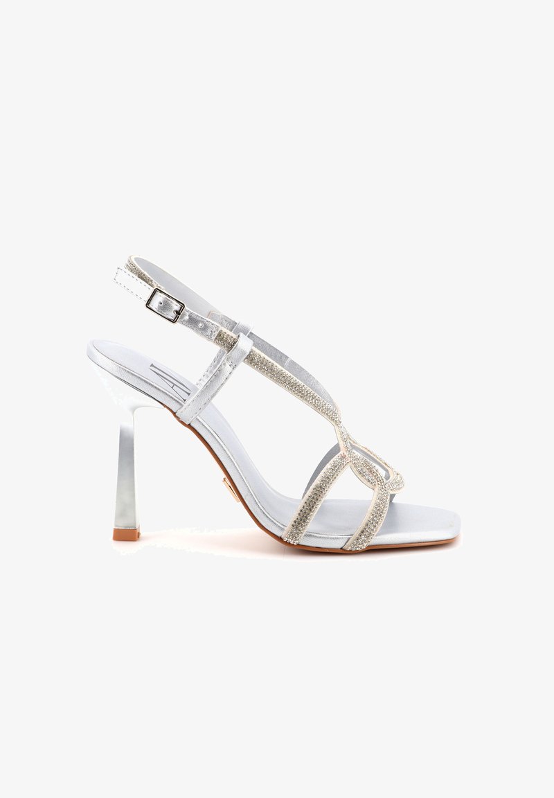 Sandal con tacco argentato caratterizzata da un design di strisce glitterate, punta aperta e un tacco metallico riflettente. Materiale superiore liscio con cinturino alla caviglia regolabile.