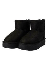 Botas de tobillo de ante negro con suela plana, que presentan una puntera redondeada y un sencillo detalle de costura a lo largo de las costuras.