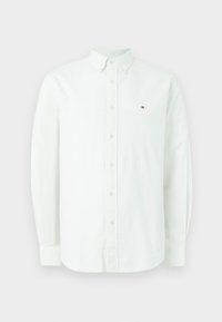 Camisa branca de manga longa feita de algodão. Apresenta um colarinho com botões, botões frontais e um pequeno logotipo no lado esquerdo do peito.