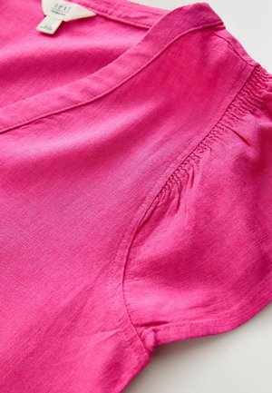 Haut en lin fuchsia avec un décolleté en V et des coutures latérales élastiquées, présentant une texture lisse et un léger éclat. Pas de motifs ou d'accents visibles.
