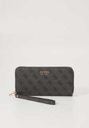 Černá peněženka z umělé kůže s embosovaným vzorem, zlatým kováním a zápěstním popruhem. Na přední straně nese logo "GUESS EST 1981".