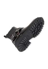Bottine en cuir noir avec un design à côtes, deux boucles ajustables et une semelle en caoutchouc texturé présentant des motifs de profondes rainures.