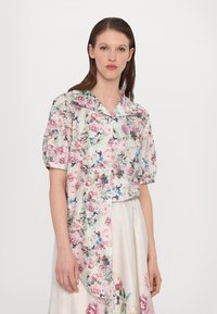Floral short-sleeve blouse features a pastel green background with pink and blue flowers. The design includes a notched collar and button closure.
