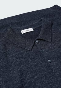 Polo bleu marine en tissu texturé, avec col, trois boutons noirs et une étiquette visible indiquant les informations de la marque.
