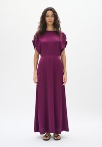 Robe maxi en violet profond, avec un décolleté carré, des manches courtes en forme de chauve-souris, et un tissu lisse et fluide qui tombe jusqu'au sol.